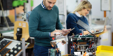 Young students of robotics preparing robot for testing in workshop