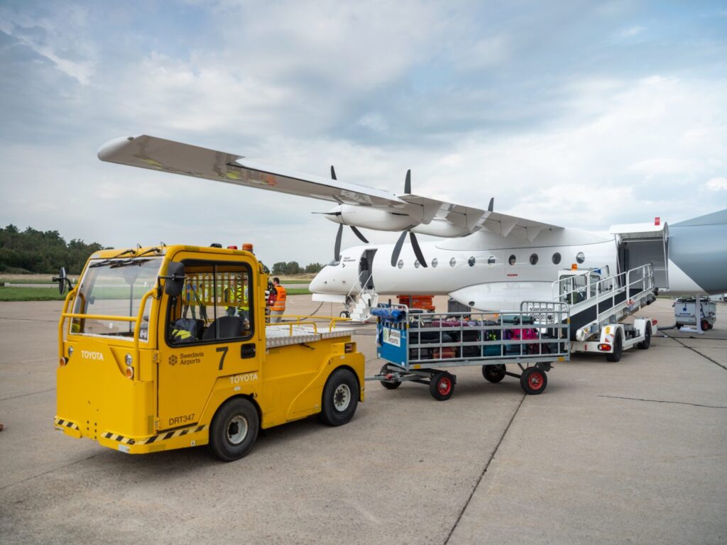 baggage truck on the runway with a Heart X1 electric model aircraft